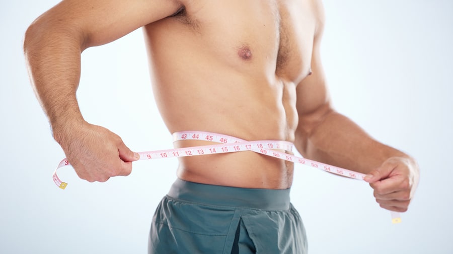 A man measuring his waist with a tape measure.