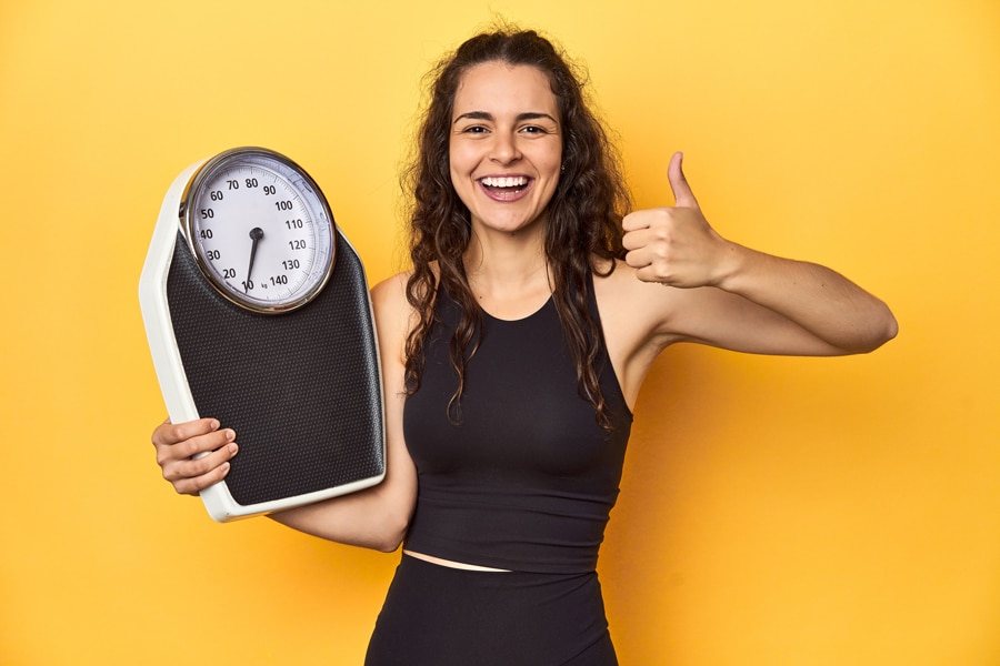 girl in a curly hair holding weighing scale