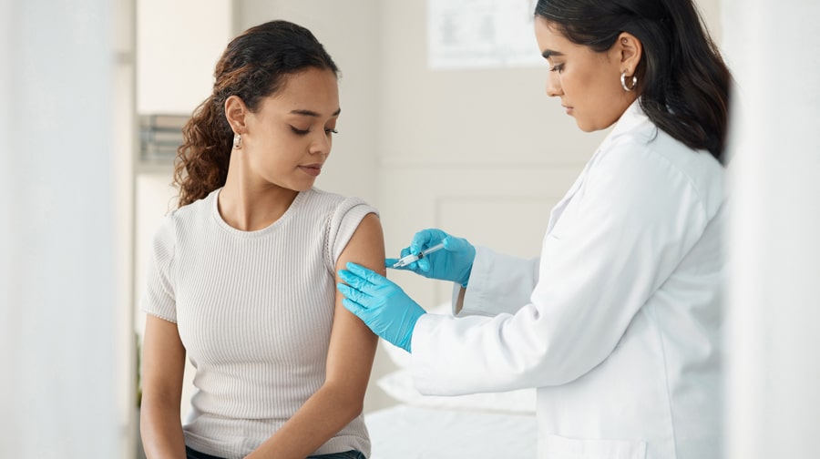 A white woman receiving a medical injection from a doctor.