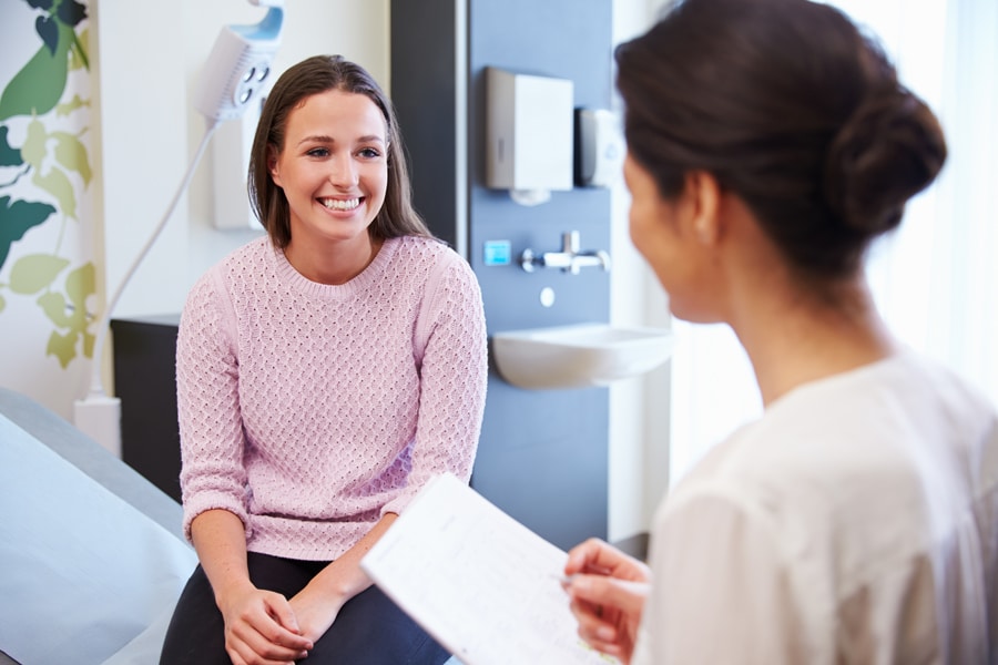 A female patient converses with a doctor in a room, seeking medical advice and discussing her health condition.