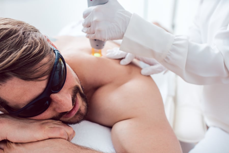 A man in a clinical setting at Ivee Restorative Care, experiencing laser treatment on his back for therapeutic benefits.