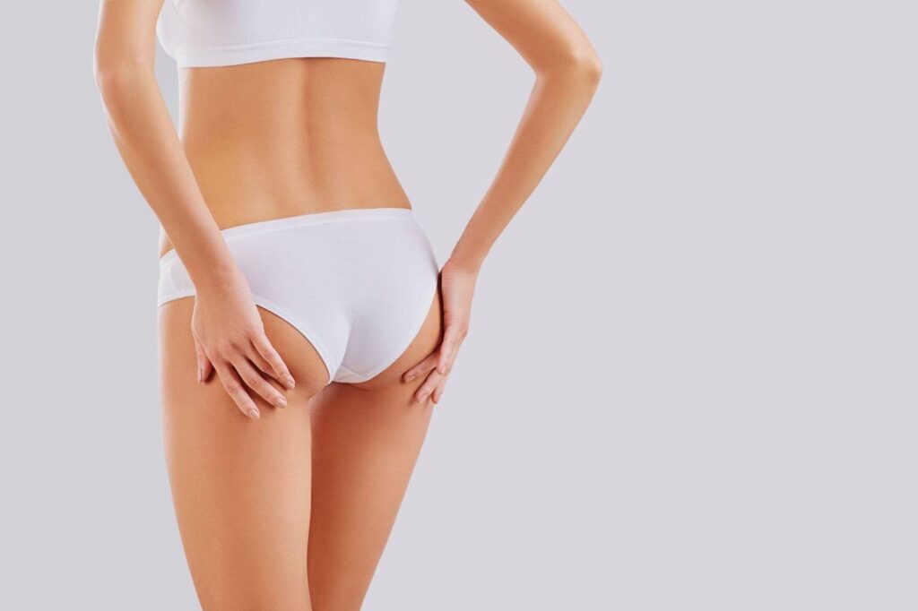 A woman poses in white underwear before a solid white backdrop