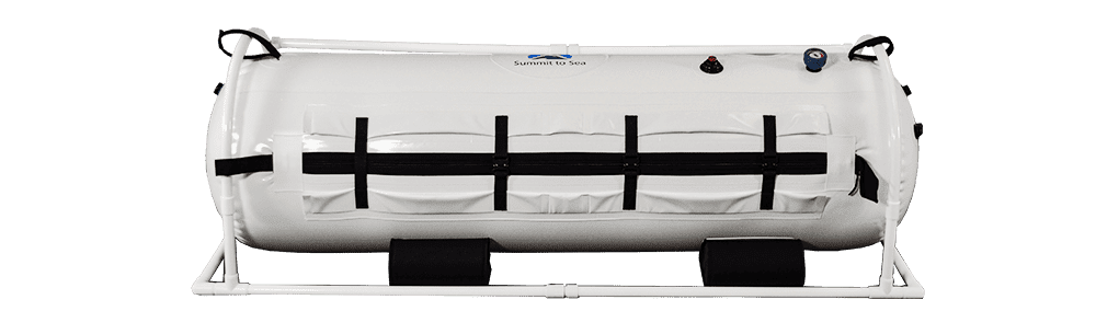 A white hyperbaric chamber with black straps and valves, mounted on a metal frame. The design is modern and functional, conveying a clinical tone.