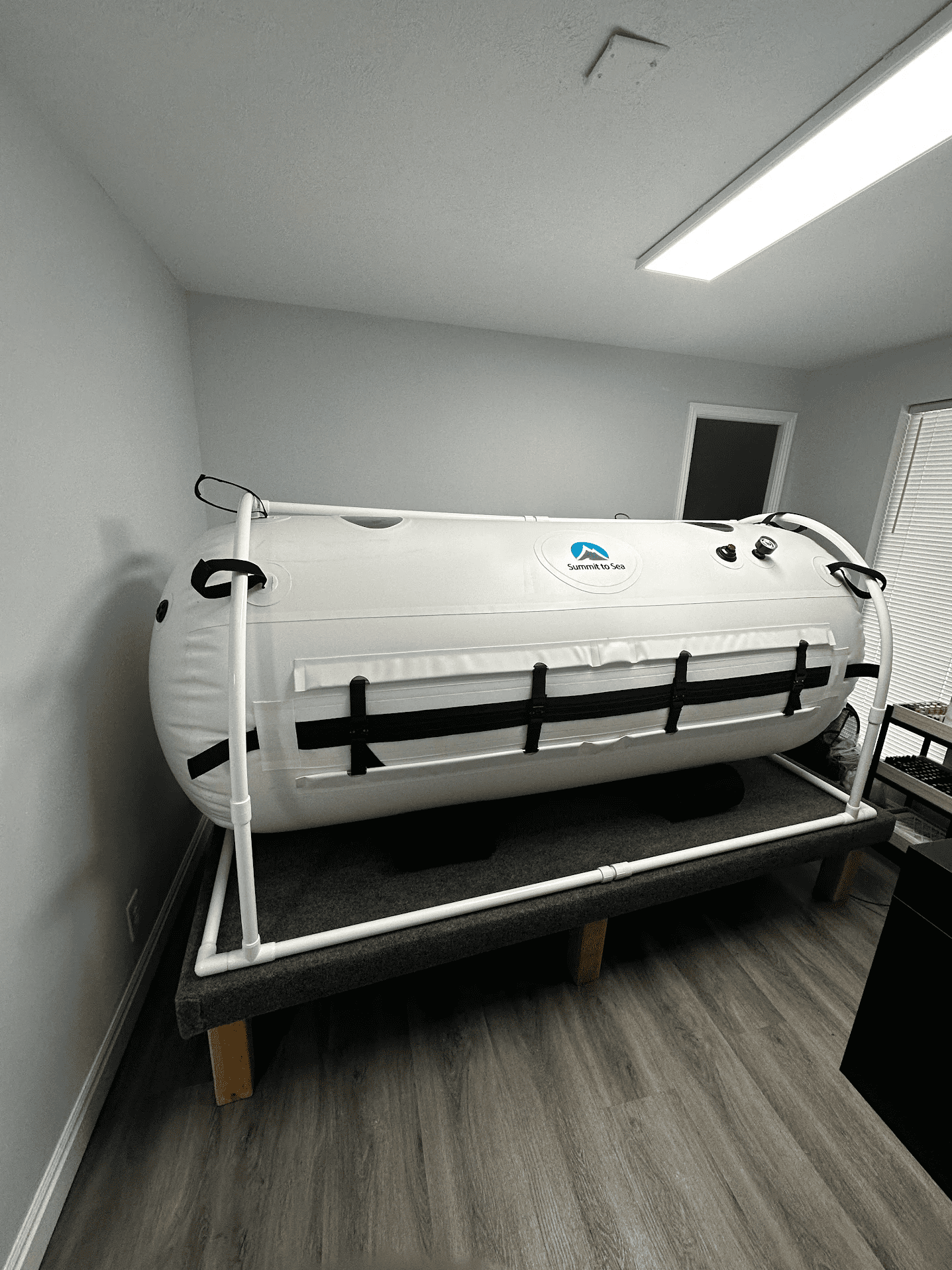 White hyperbaric chamber inside a room with a window. The chamber is labeled "Summit to Sea."