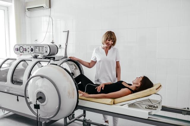 A woman lies on a hospital bed surrounded by medical equipment in a well-lit hospital room