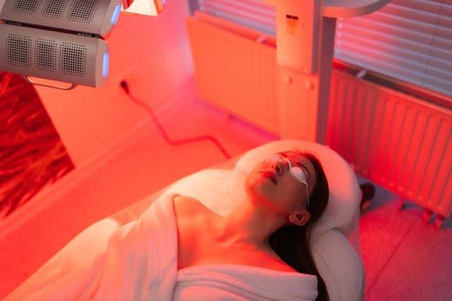 A woman relaxes in a spa room illuminated by soft red light creating a calming and serene atmosphere