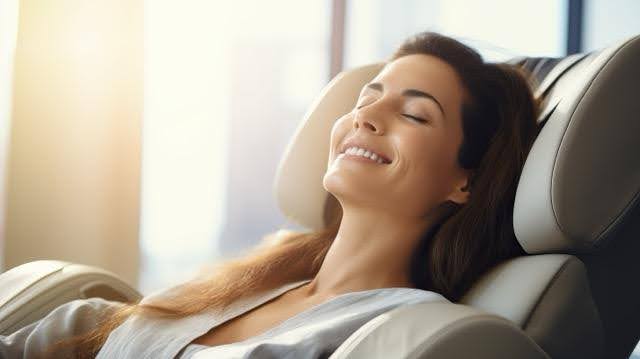 A woman sits in a massage chair visibly relaxed and enjoying a soothing massage experience
