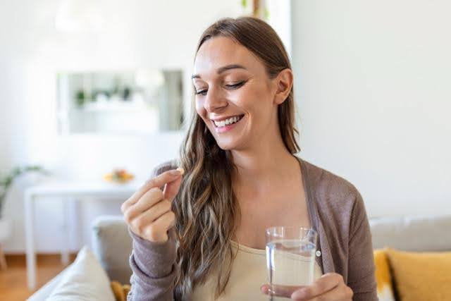 A smiling woman holds a glass of milk radiating joy and warmth in a bright setting