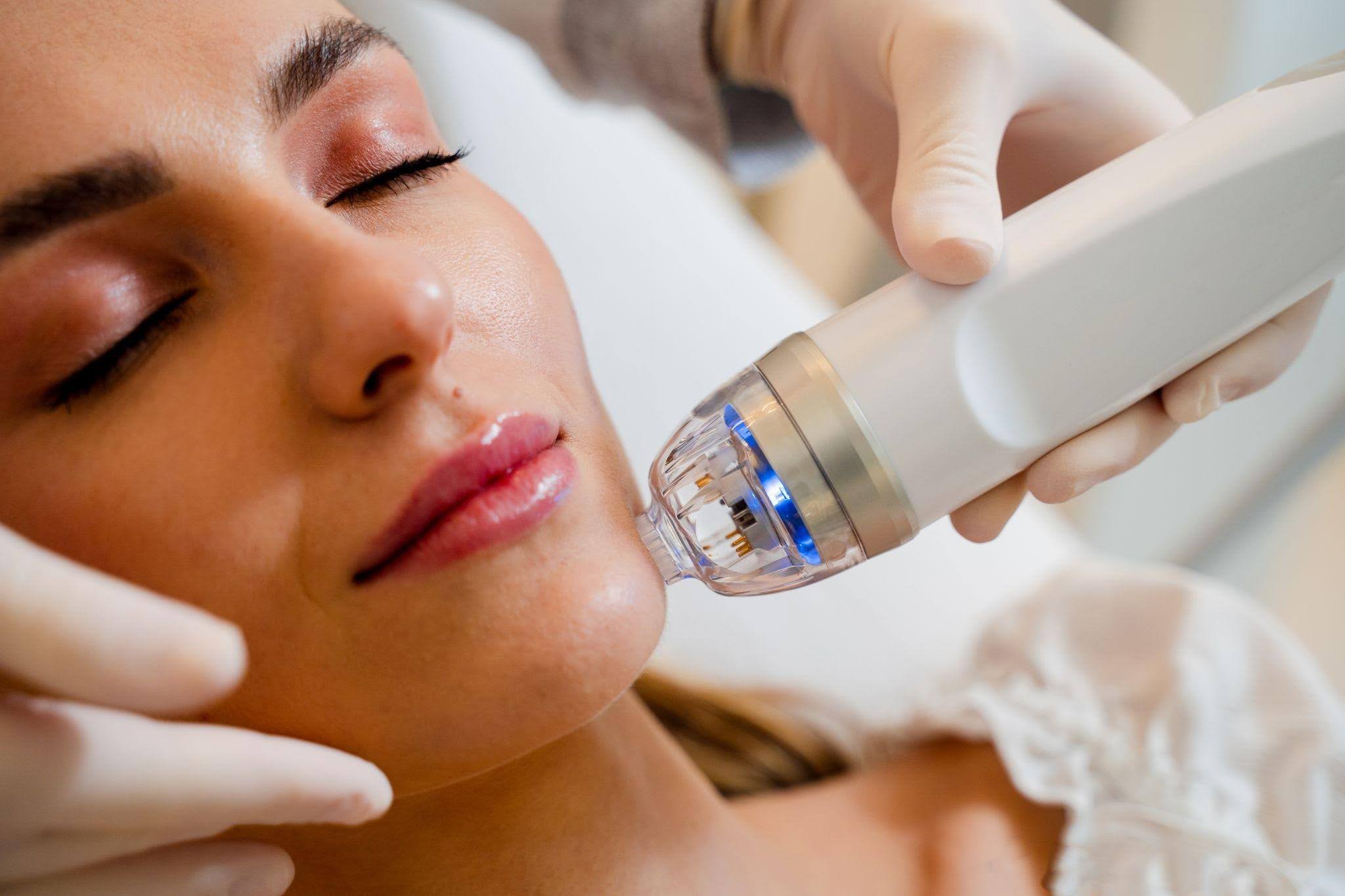 A woman receiving a facial treatment while using a facial device for skincare enhancement