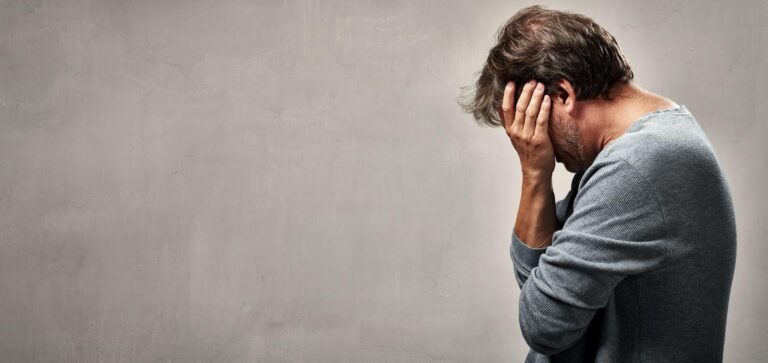 A man appears troubled holding his head in his hands in a moment of despair