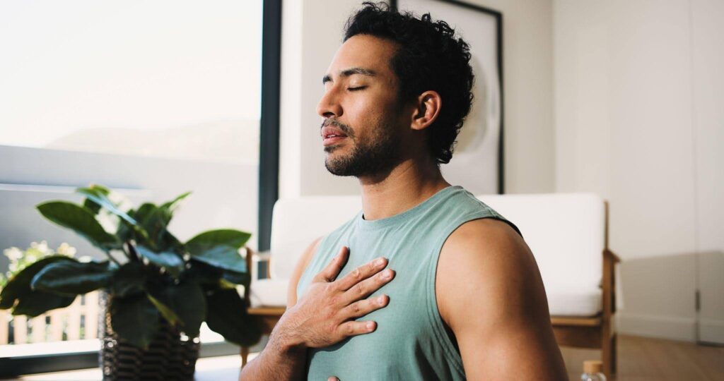 A man sits in a yoga pose demonstrating focus and tranquility in a serene environment