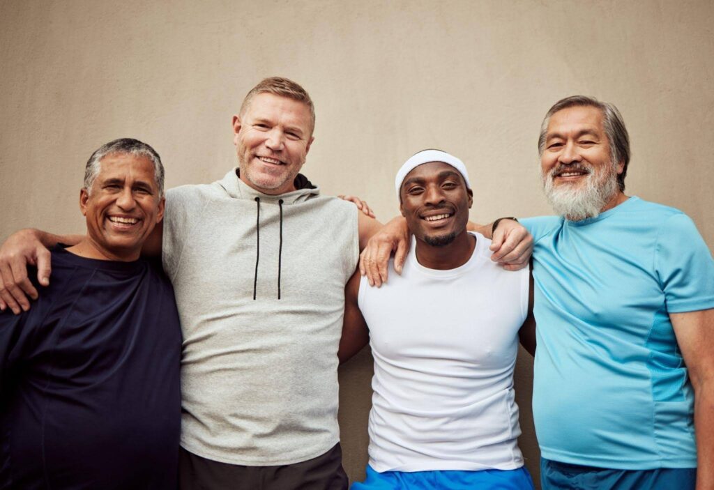 Four men standing together with one man in the center smiling at the camera